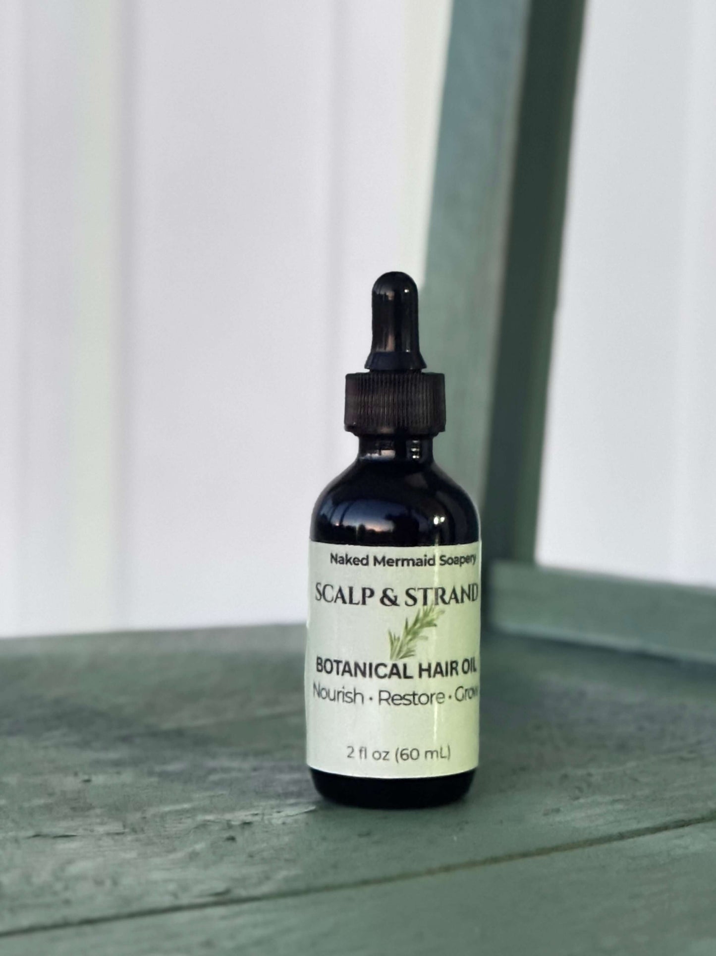 2 oz bottle of herbal hair oil with botanical ingredients for nourishing the scalp, reducing frizz, and promoting natural hair growth