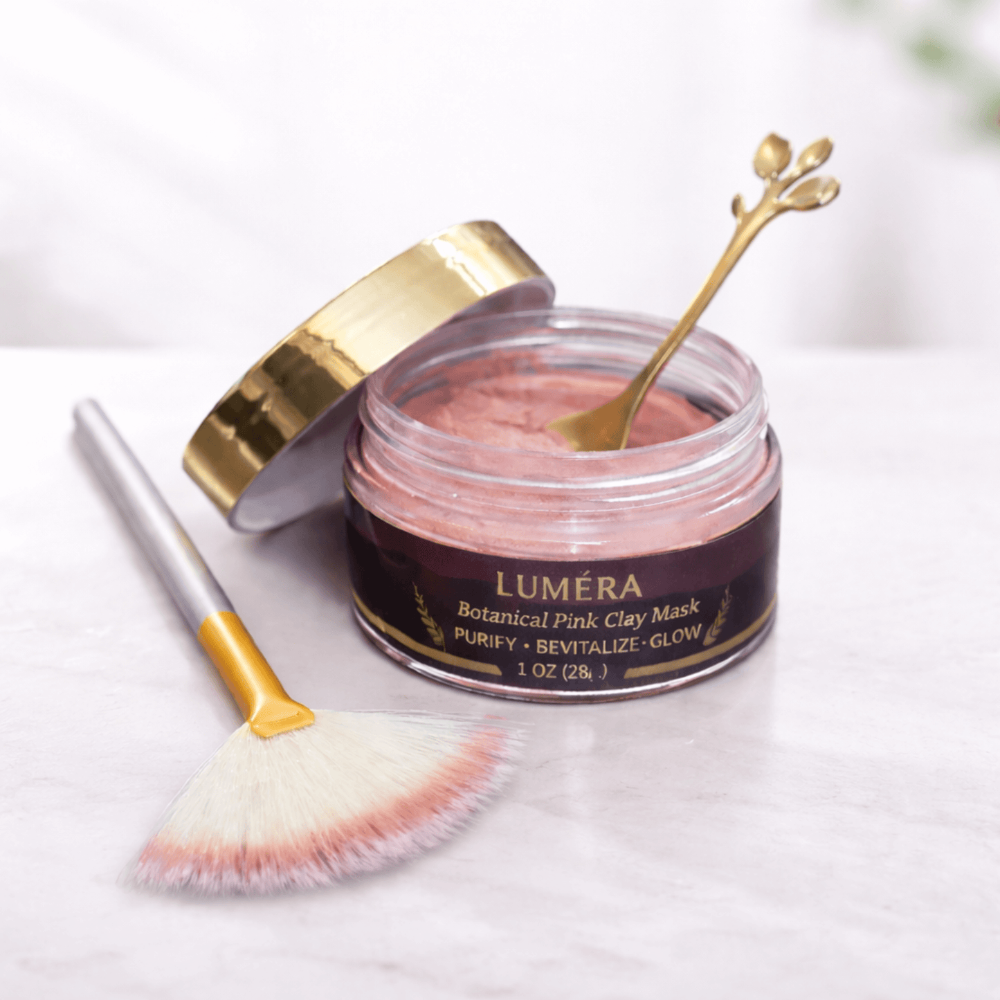 Luxury skincare gift set featuring Luméra Botanical Pink Clay Mask with wooden spatula on a marble surface.