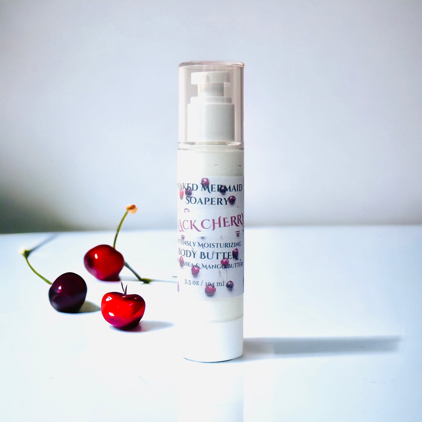 a tube of body butter next to two cherries