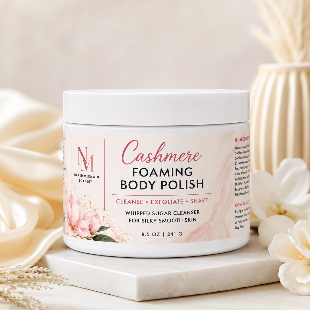 Cashmere Foaming Body Polish by Naked Mermaid Soapery in an 8.5 oz white jar with a luxurious cream and gold label. This whipped sugar body polish gently cleanses, exfoliates, and creates a rich lather for shaving while leaving skin silky smooth and delicately scented with the warm, comforting Cashmere fragrance.