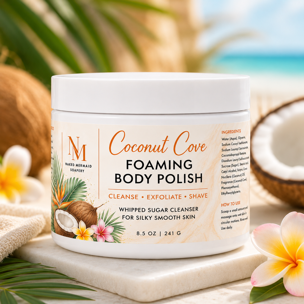 Coconut Cove Foaming Body Polish by Naked Mermaid Soapery in an 8.5 oz white jar with a tropical coconut-inspired label. This whipped sugar body polish gently cleanses, exfoliates, and creates a rich lather for shaving while leaving skin silky smooth and fragranced with creamy coconut, juicy mango, and a hint of fresh lemon.