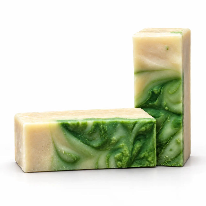 Two rectangular handmade soap bars with a marbled swirl pattern of green and cream, set against a plain white background.