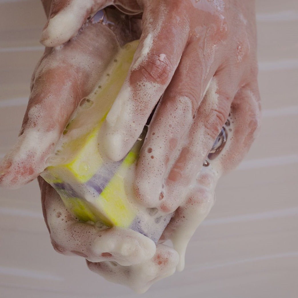 a person is washing their hands with a soap bar made by naked mermaid soapery LLC