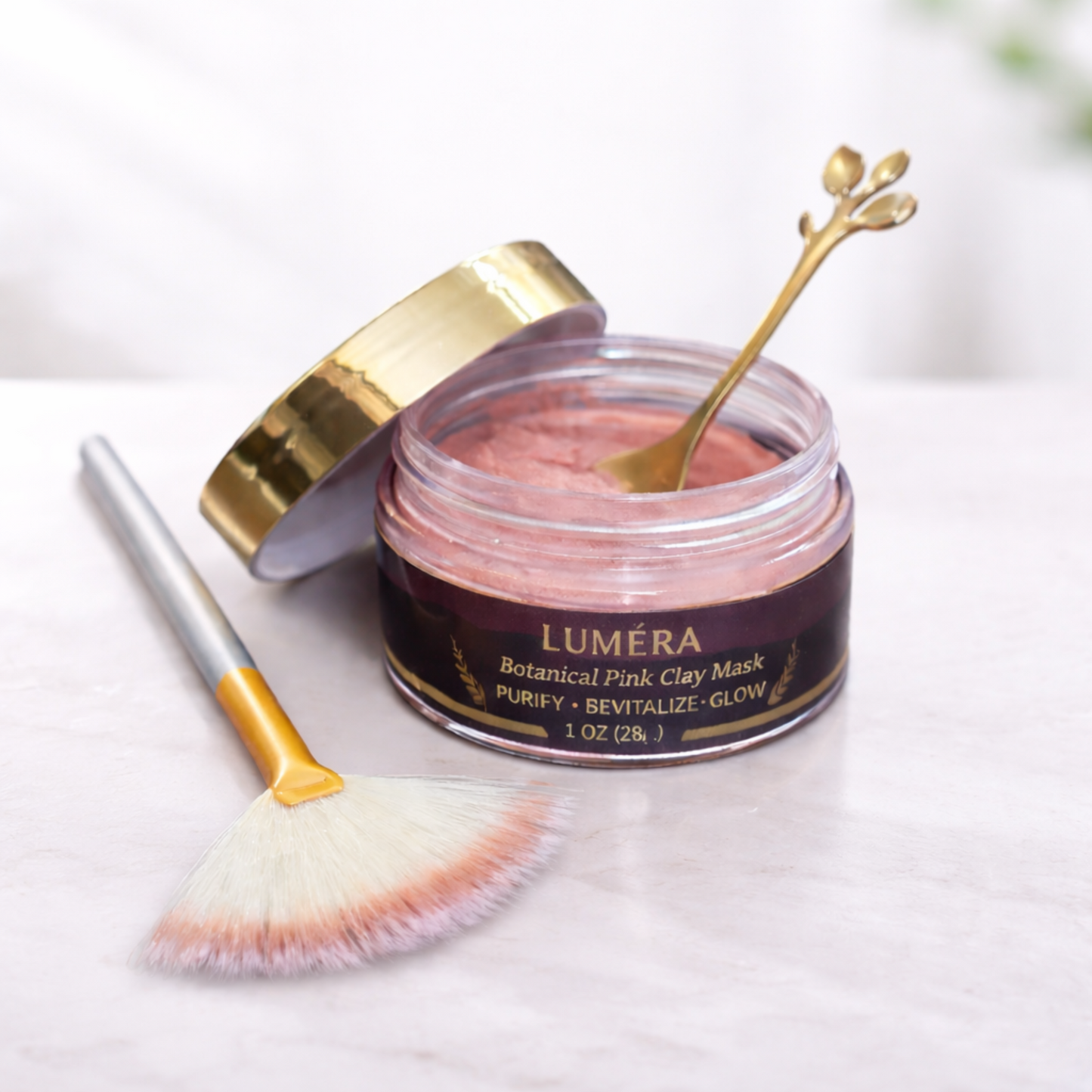 Open jar of Luméra Botanical Pink Clay Mask with gold spoon and fan brush on a clean white background, featuring a rose clay facial mask made with Kaolin (Rose) Clay, Illite (French Pink Clay), Rosa Canina Fruit Powder, and Aloe Barbadensis Leaf Powder.