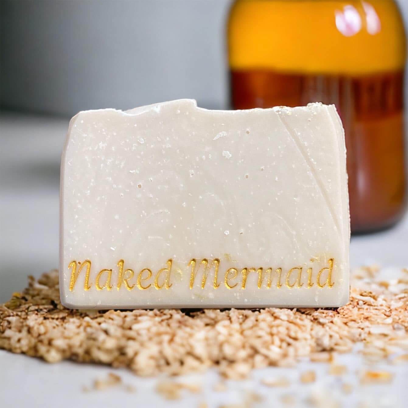 Bar of soap with 'Naked Mermaid' branding on a textured surface.