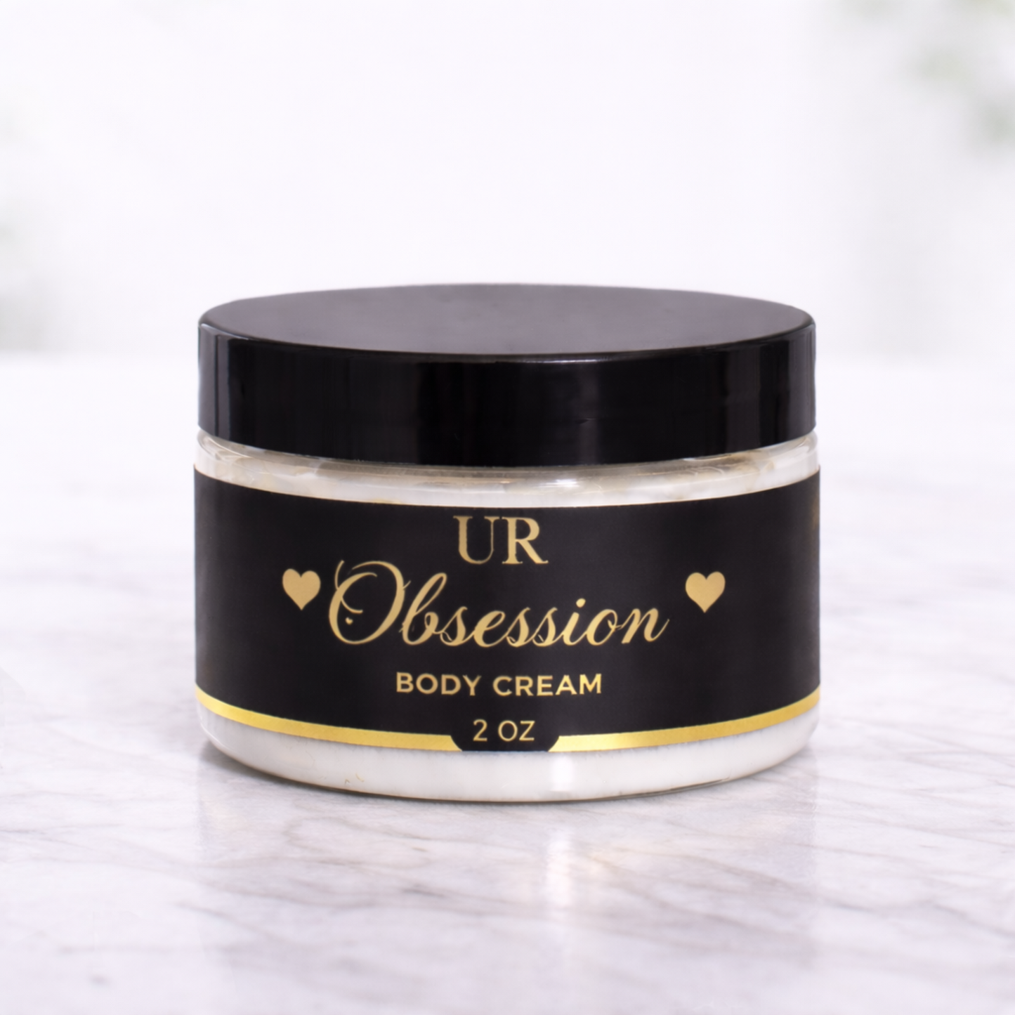 UR Obsession 2 oz body cream with a seductive blend of sweet and floral notes, formulated with shea butter, mango butter, jojoba oil, and hyaluronic acid for deep hydration and soft, glowing skin.