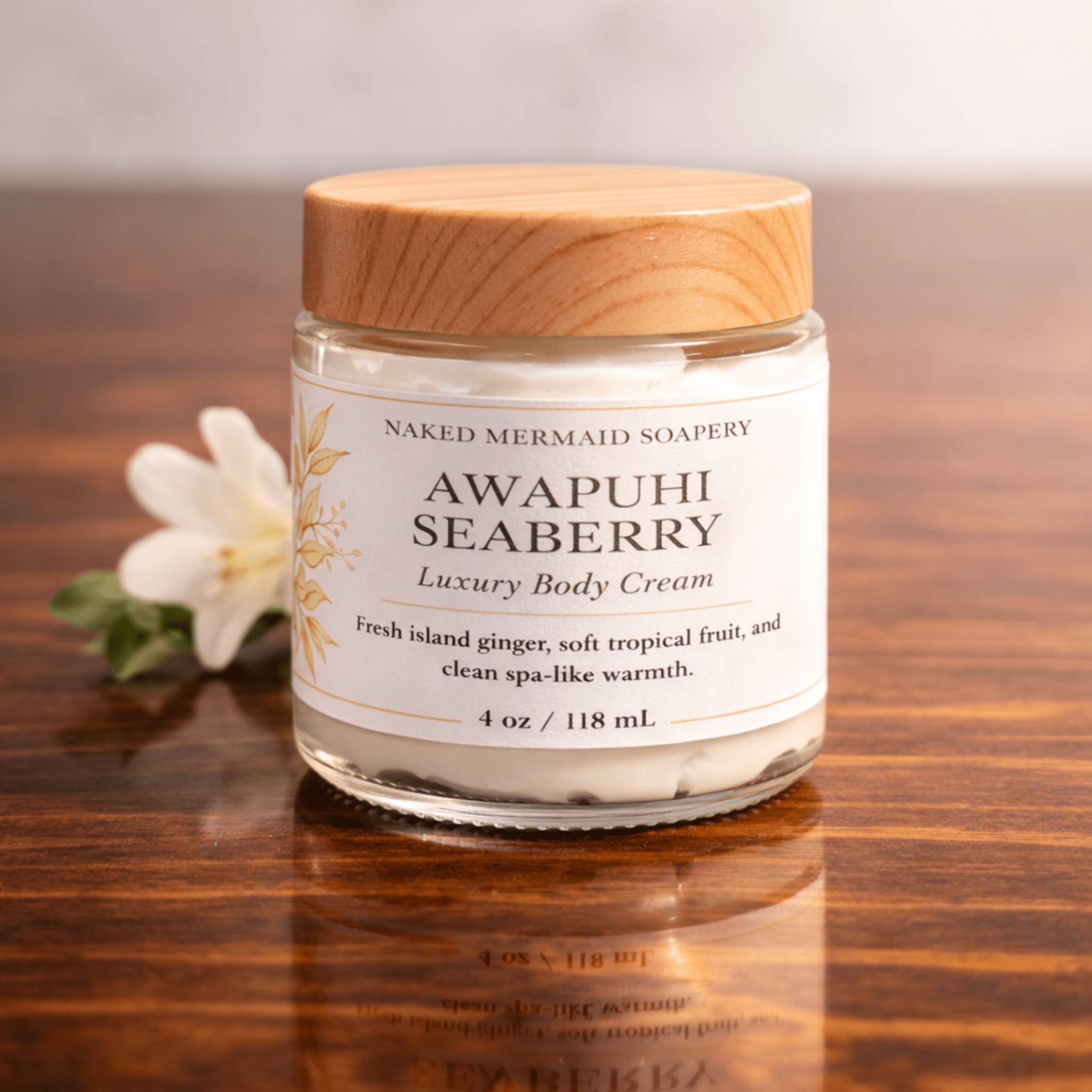 Awapuhi Seaberry Luxury Body Cream in glass jar with wood lid, natural skincare on wood surface with white flower