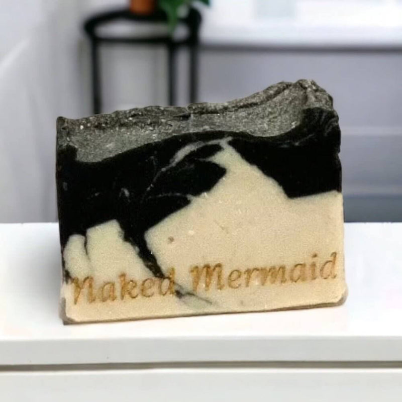 Handcrafted natural soap bar with black and cream swirls, embossed 'Naked Mermaid' text