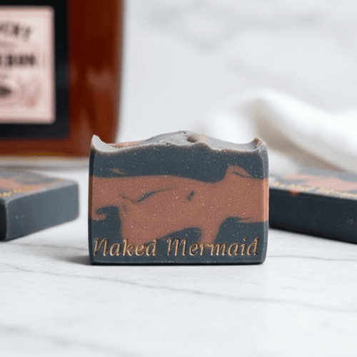 Handcrafted natural soap bar with 'Naked Mermaid' imprint, artisan skincare on marble surface